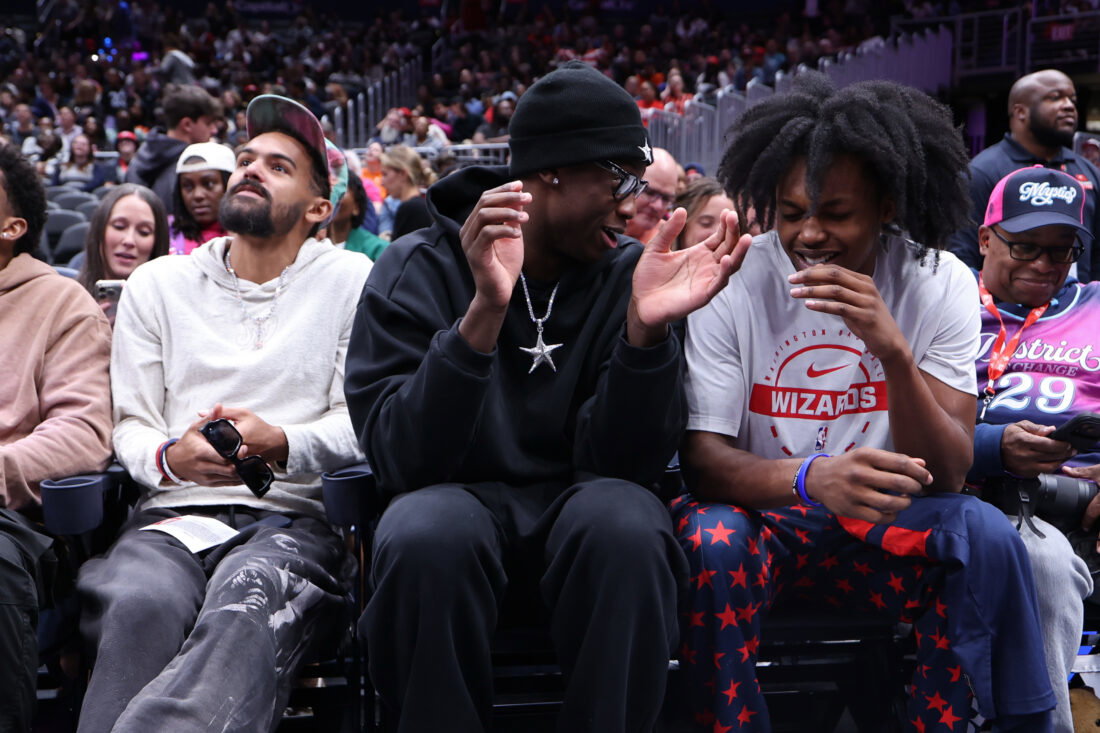 Sep 24, 2026; Washington, District of Columbia, USA; (L-R) Washington Wizards players Trae Young, AJ Dybantsa, and Bub Carrington sit courtside at the game between the Washington Mystics and Chicago Sky at Capital One Arena. Mandatory Credit: Geoff Burke-Imagn Images