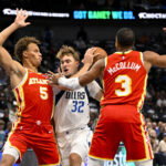 Oct 16, 2026; Dallas, Texas, USA; Dallas Mavericks forward Cooper Flagg (32) drives to the basket between Atlanta Hawks guard Dyson Daniels (5) and guard CJ McCollum (3) during the first quarter at American Airlines Center. Mandatory Credit: Jerome Miron-Imagn Images