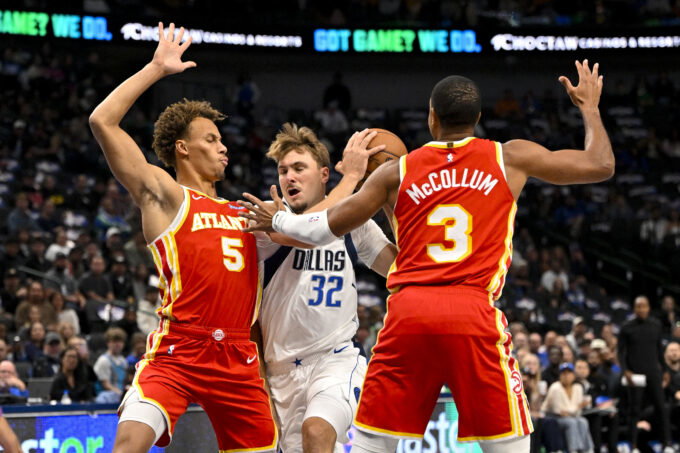 Oct 16, 2026; Dallas, Texas, USA; Dallas Mavericks forward Cooper Flagg (32) drives to the basket between Atlanta Hawks guard Dyson Daniels (5) and guard CJ McCollum (3) during the first quarter at American Airlines Center. Mandatory Credit: Jerome Miron-Imagn Images